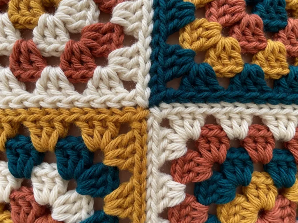 Close-up of a granny stitch crochet blanket showing the clustered square pattern and colour joins