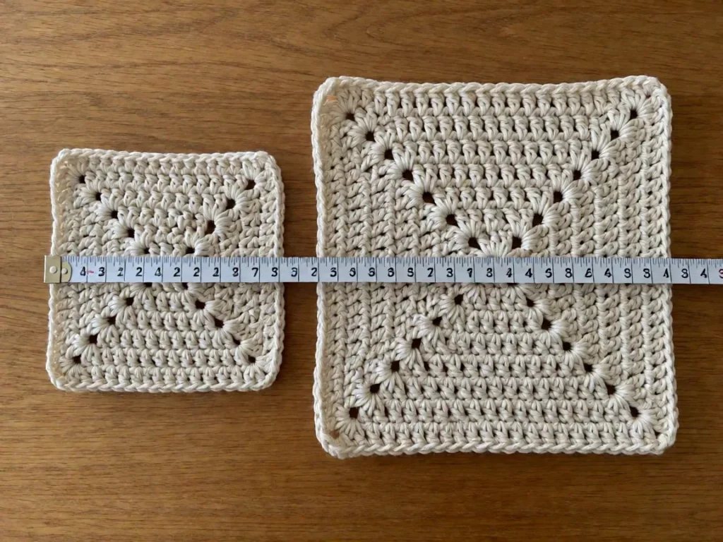 A tape measure across a crocheted gauge swatch laid flat on a wooden surface